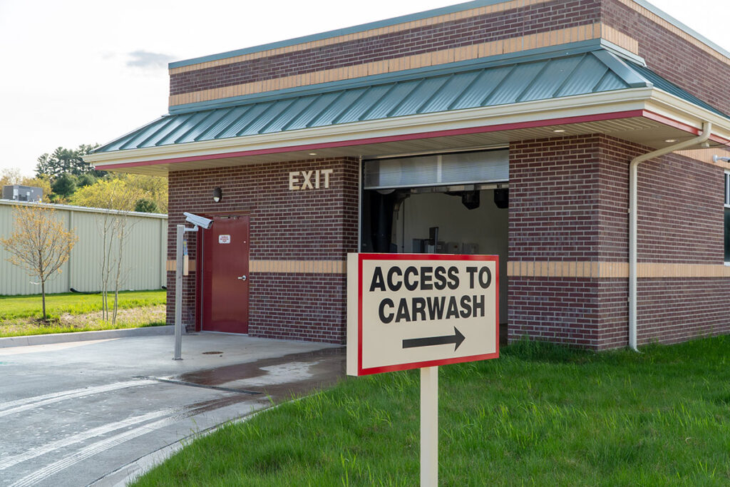 A sign reading "Access to Carwash" with an arrow pointing right is in front of a red brick building with a metal roof labeled "Exit."